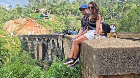 Couple sitting on a wall overlooking the Nine Arch Bridge.