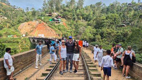 Group of people standing on railway tracks at Nine Arch Bridge.