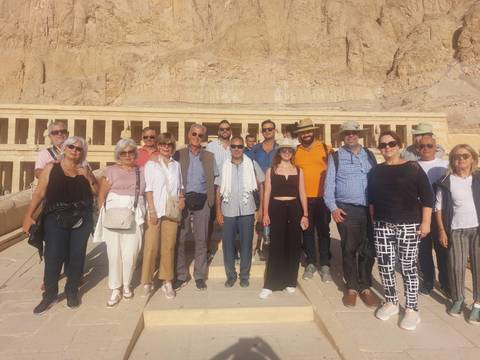       Group of tourists posing in front of an ancient temple.
  