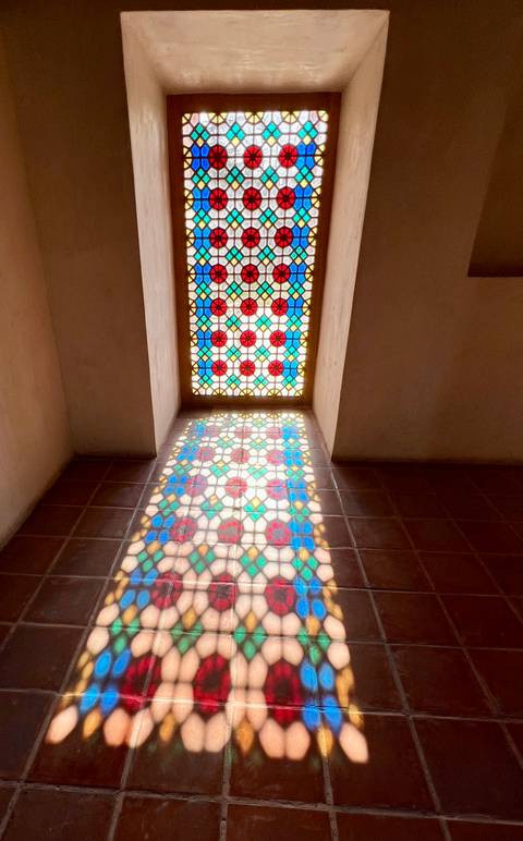       Stained glass window with colorful pattern and its reflection.
  