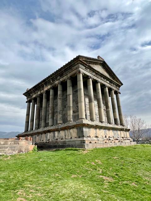       Ancient temple with large stone columns under a cloudy sky.
  