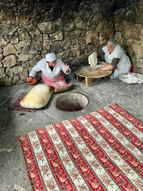       Two women making bread in a traditional way.
  