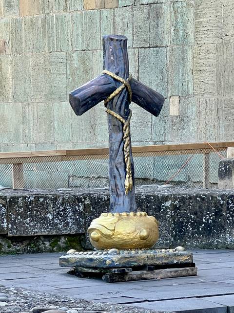       Wooden cross sculpture tied with ropes.
  