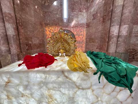       Decorative altar with vibrant fabrics and a golden artwork.
  