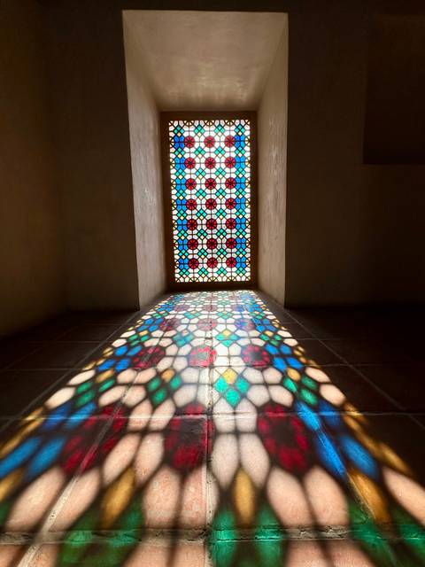       Stained glass window with colorful light reflections on the floor.
  