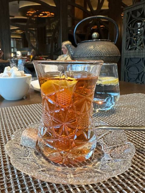       Glass of tea with an orange slice and sugar on a tray.
  
