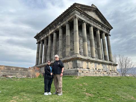       Two people posing in front of an ancient temple.
  