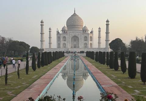       The Taj Mahal with a reflection pool and visitors.
  