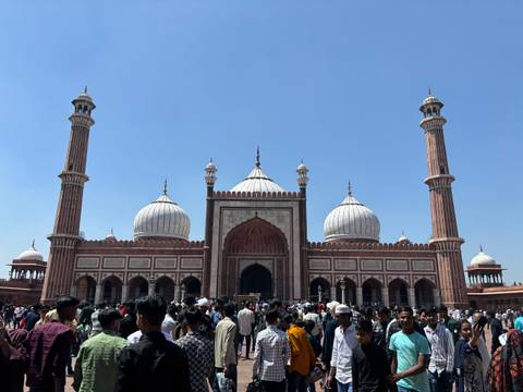       A large mosque with a crowd of people in front.
  