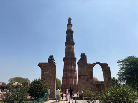       Qutub Minar in front of a clear blue sky.
  