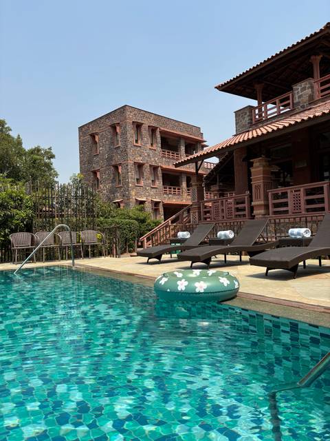       Swimming pool with sun loungers at a hotel.
  