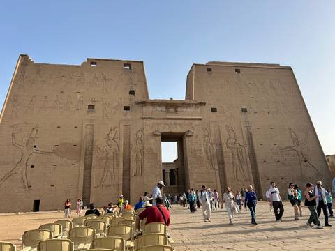 People exploring a large ancient Egyptian site with engravings.