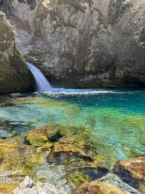 Blue pool of water with waterfall in the background.