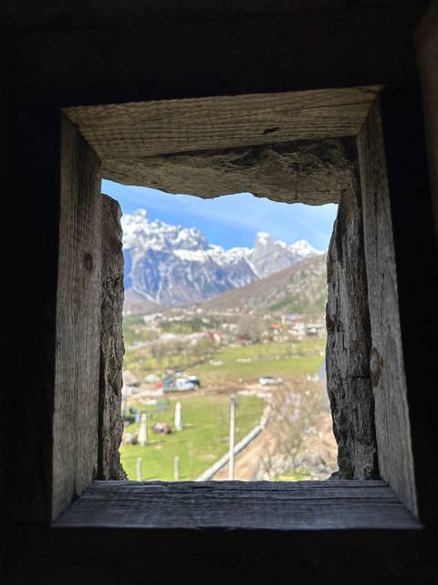 View of mountains through a rustic wooden window.