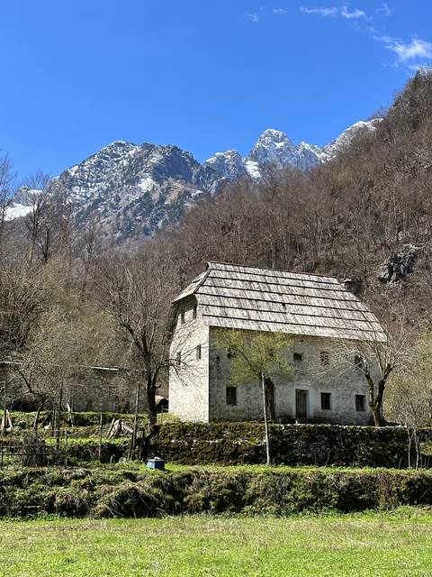       Old stone house in wooded mountain area.
  