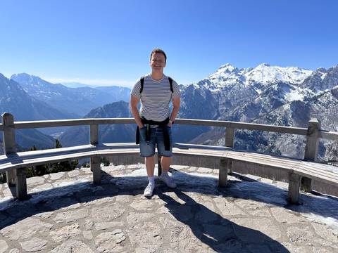       Person posing at a mountain viewpoint with scenic views.
  