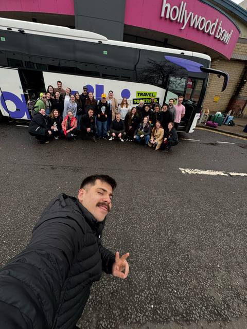 Group photo with a bus and luggage in the background.