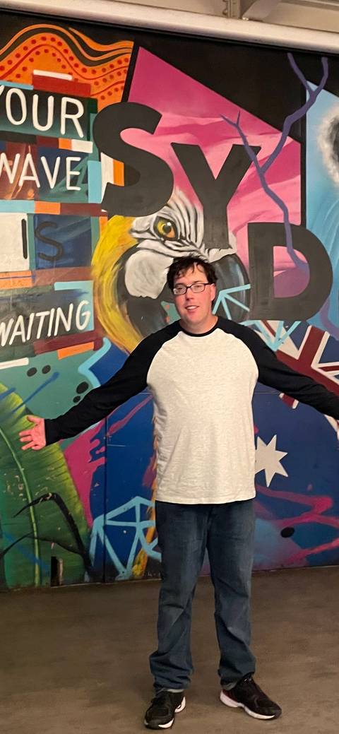 Person posing in front of a colorful mural.