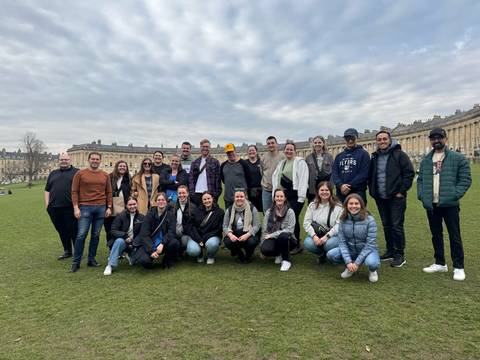 Large group of people posing in front of historic buildings.