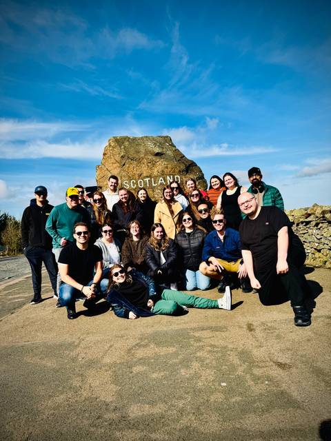 Group photo in front of a stone monument with 'Scotland' inscribed.