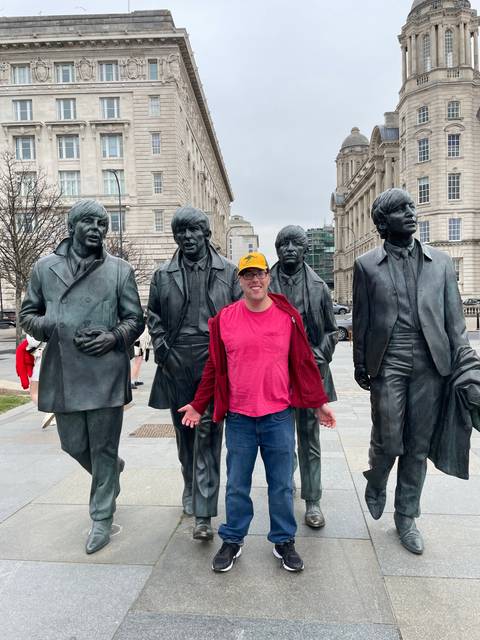 Tourist posing with Beatles statues.