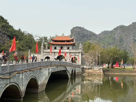 Historic bridge leading to a gate flanked by mountains.