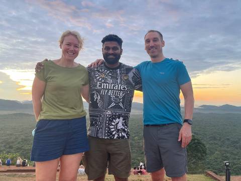       Couple with guide against a backdrop of greenery.
  