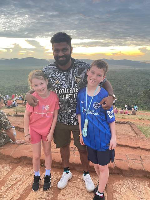 Man with two kids smiling with a scenic background.