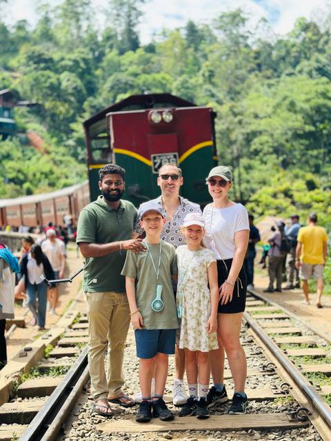 Family posing in front of a colorful train.