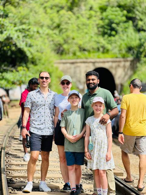       People posing at a train station entrance.
  