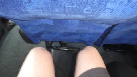 A view of knees and a bus seat.