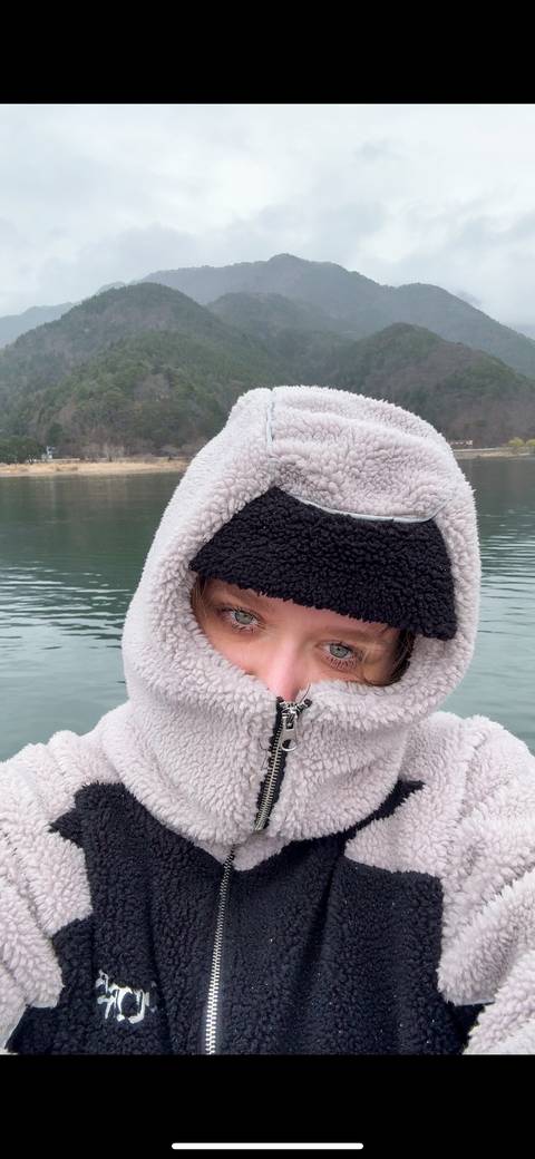 A person in warm clothing near a body of water.