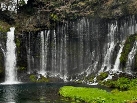 Waterfall cascading over dark rocks into a pond.
