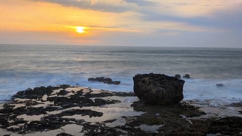       Rocky shore with sunset over the ocean.
  