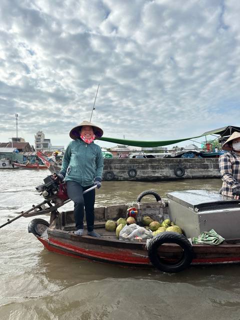       Woman standing on a boat in a busy river scene.
  