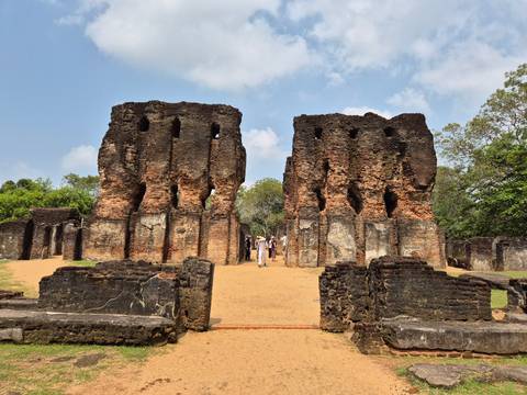       Ruins of ancient stone buildings with people walking.
  