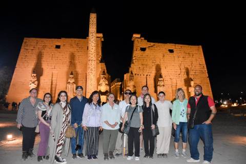 Group of people in front of a large illuminated temple at night.