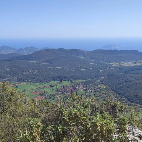       Expansive view of valleys and hills with ocean in the distance.
  