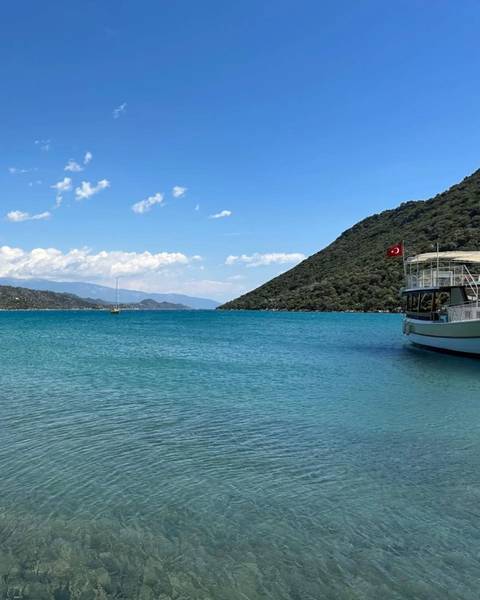       Scenic view of a bay with a boat and Turkish flag.
  
