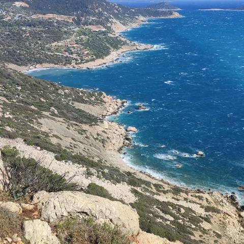       Rocky coastline with blue sea and waves.
  