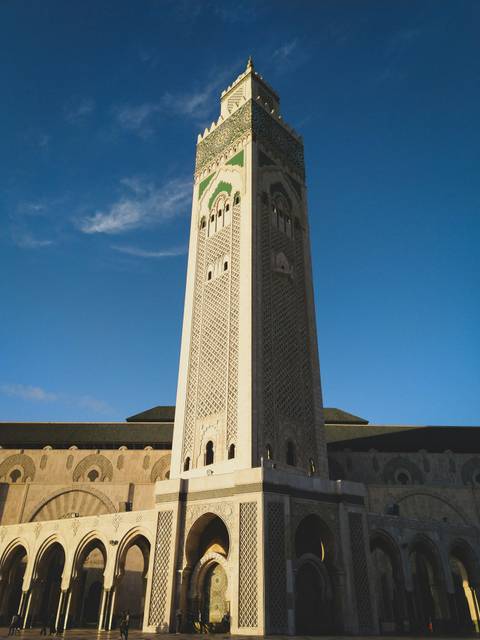 Tall minaret of a mosque against a blue sky.