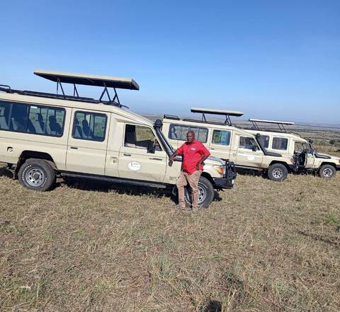 Guide posing with safari vehicles.
