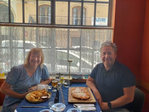 Two people sitting at a table enjoying a meal by a window.