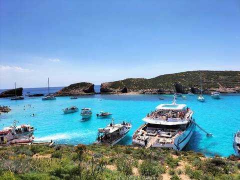 Turquoise waters with boats and rocky cliffs.