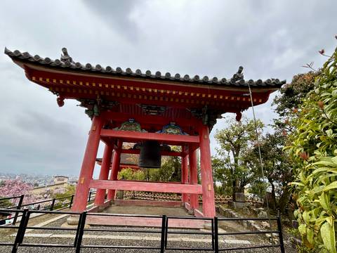 Traditional Japanese bell tower surrounded by trees.