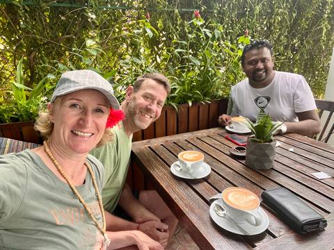 Three people enjoying coffee at an outdoor cafe.
