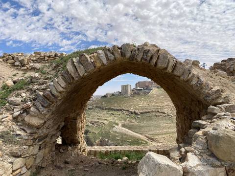 Ancient stone archway overlooking a modern city.