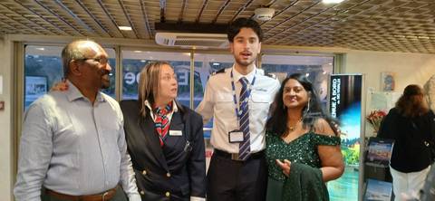 Four people posing together on a ship with interior details visible.