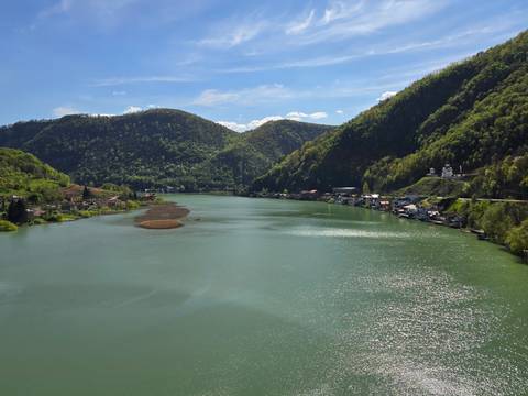 Serene lake surrounded by green hills under a clear sky.