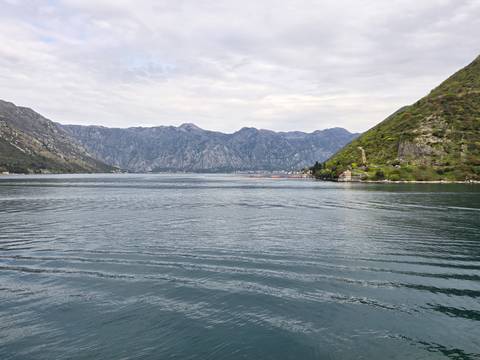       Large body of water with mountain backdrop under overcast skies.
  